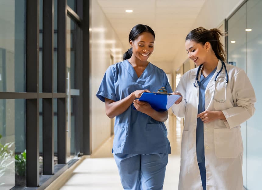 A group of medical professionals, including doctors and nurses, walk together down a hospital hallway, engaged in conversation.